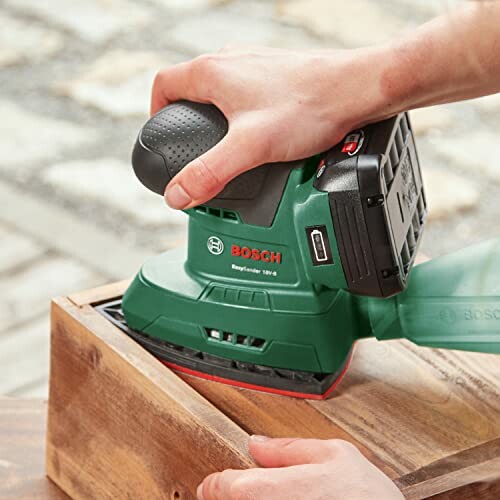 Person using Bosch electric sander on wood surface