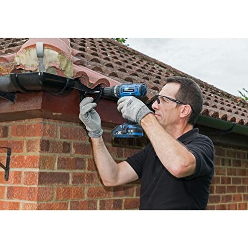 Man using a drill to repair a roof gutter.