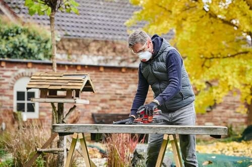 Man wearing mask sanding a wooden table outdoors