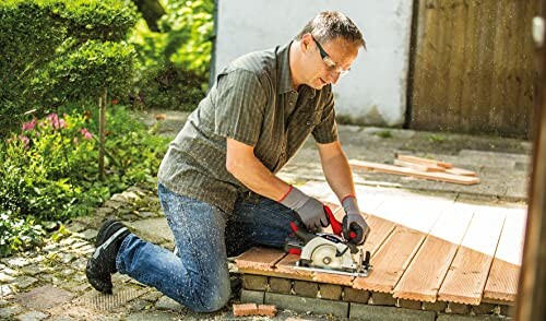 Man cutting wood with a circular saw outdoors.