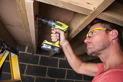 Man using a Ryobi drill on a wooden ceiling frame.