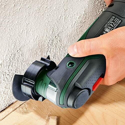 Person using oscillating tool to cut into a wall.