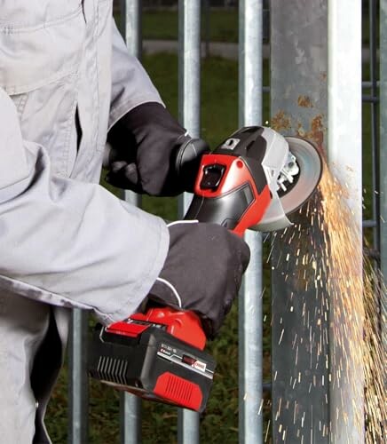 Person using an angle grinder on a metal surface, creating sparks.