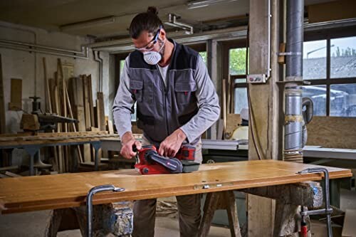 A person sanding a wooden board in a workshop.